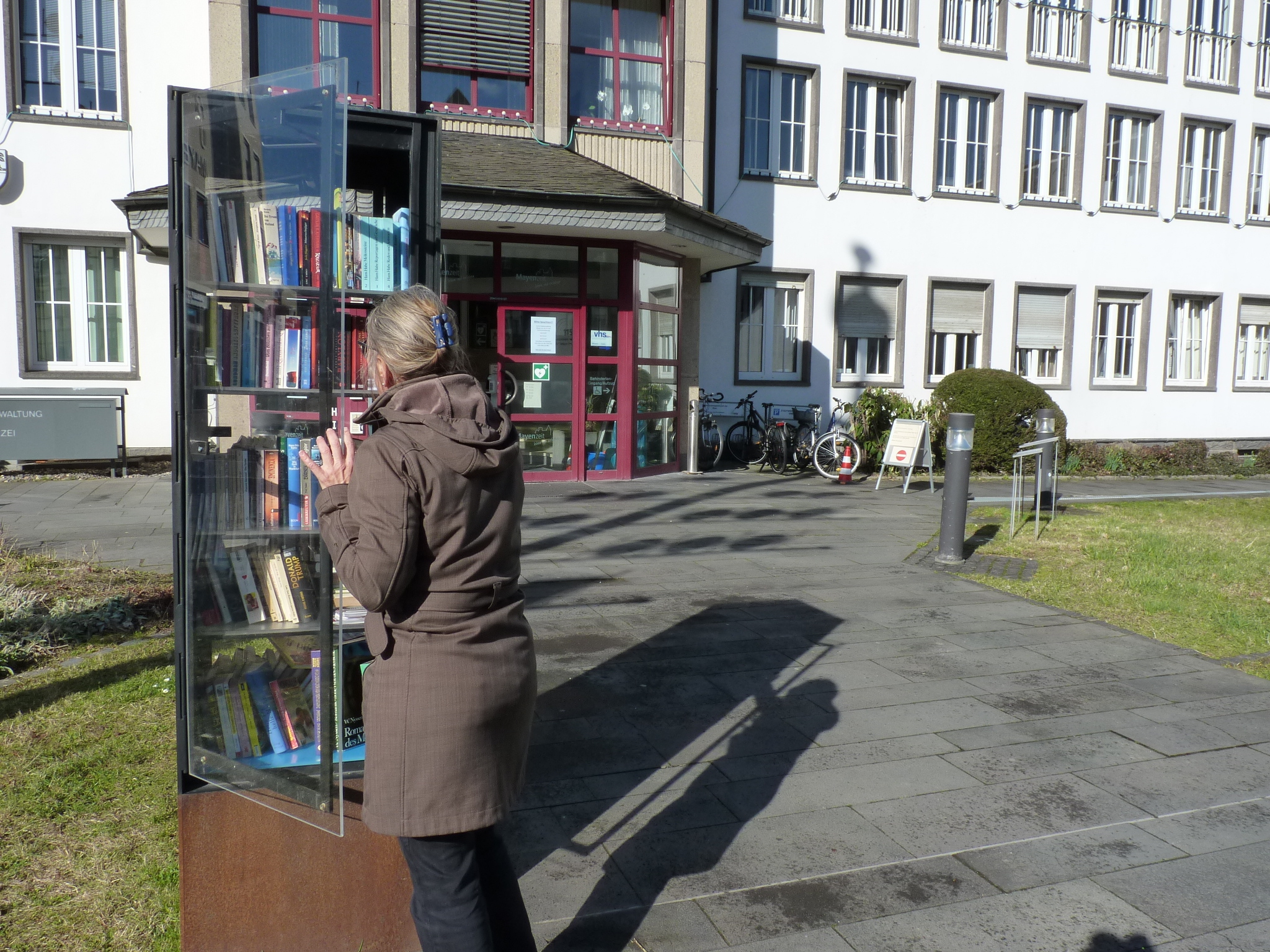 Frau steht vor Bücherschrank vor der Stadtverwaltung Mayen