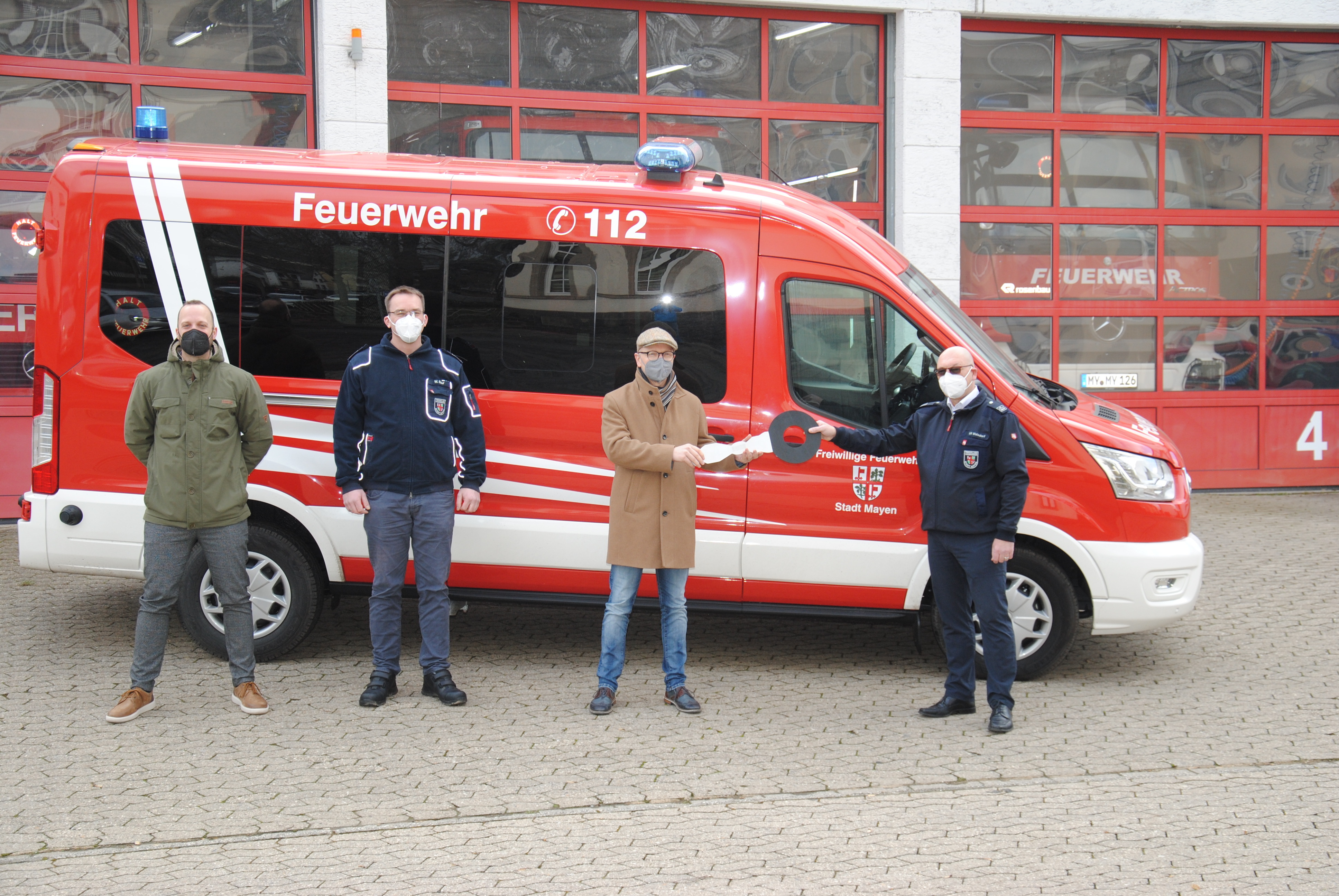 Bereichsleiter Jan Kröll, Zugführer Löschzug Kernstadt Wolfgang Saur, Oberbürgermeister Dirk Meid und stellvertretender Wehrleiter Uli Walsdorf stehen vor dem neuen Mannschaftstransportwagen mit einem großen Schlüssel