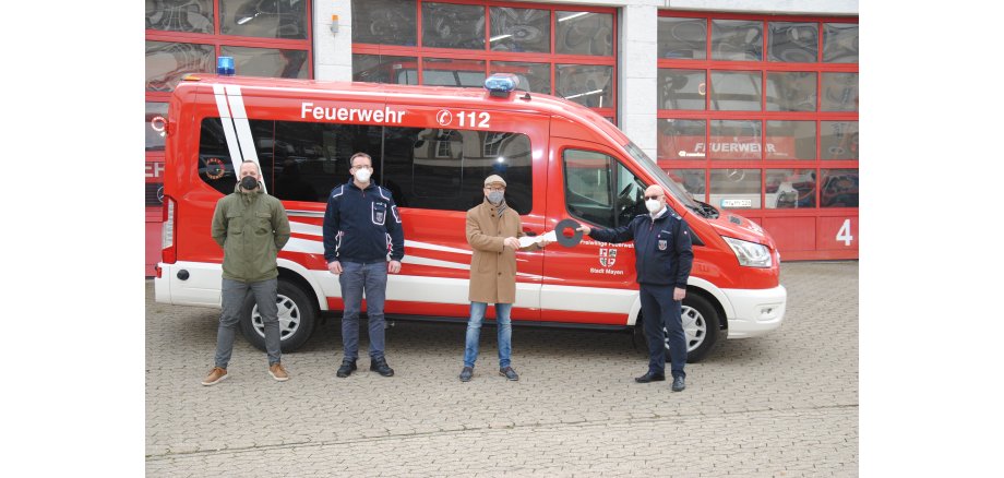 Bereichsleiter Jan Kröll, Zugführer Löschzug Kernstadt Wolfgang Saur, Oberbürgermeister Dirk Meid und stellvertretender Wehrleiter Uli Walsdorf stehen vor dem neuen Mannschaftstransportwagen mit einem großen Schlüssel 