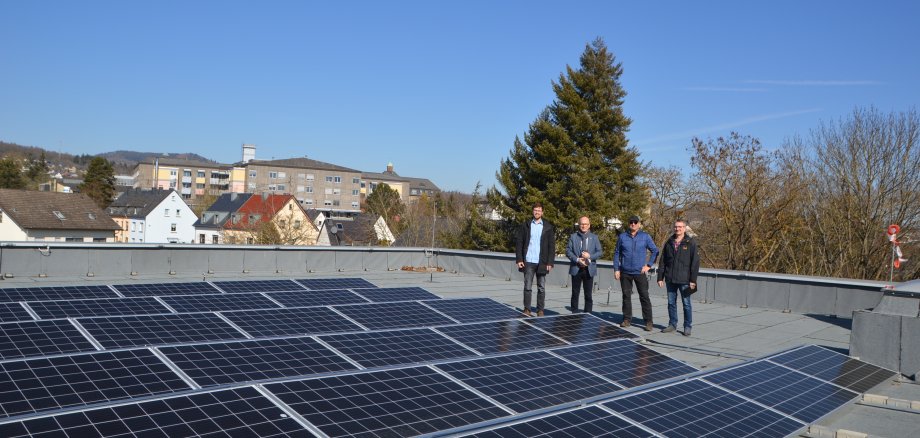 Vier Personen auf einem Dach mit Photovoltaik.