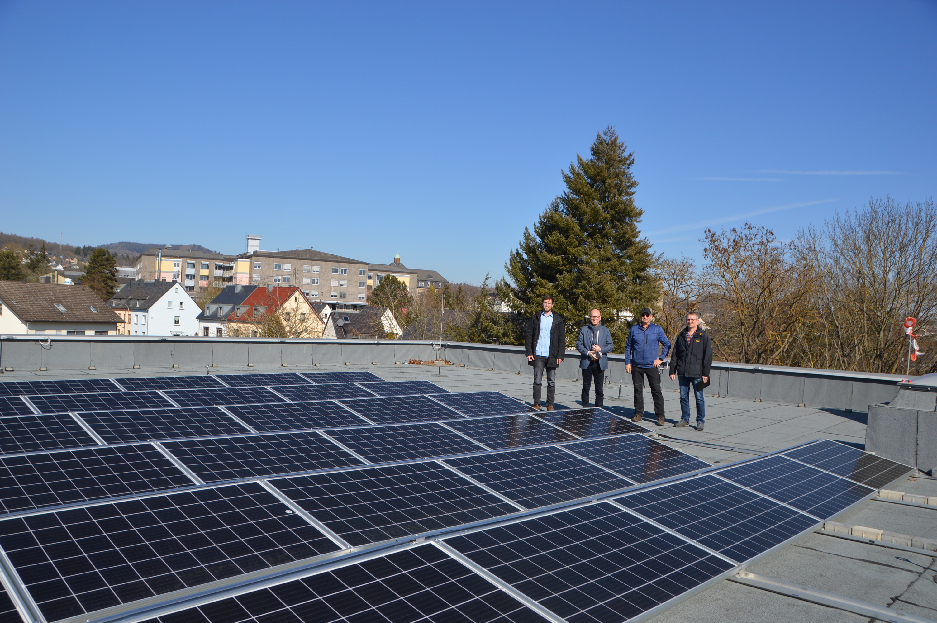 Vier Personen auf einem Dach mit Photovoltaik.
