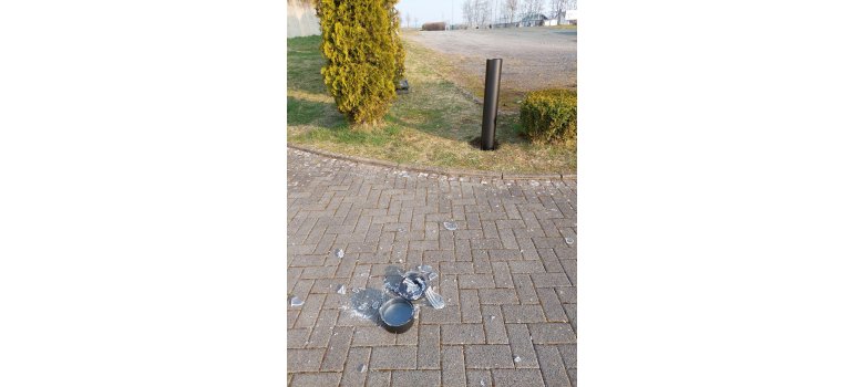 zerstörte Lampe, Glassplitter auf dem Boden am Rand Grasfläche 