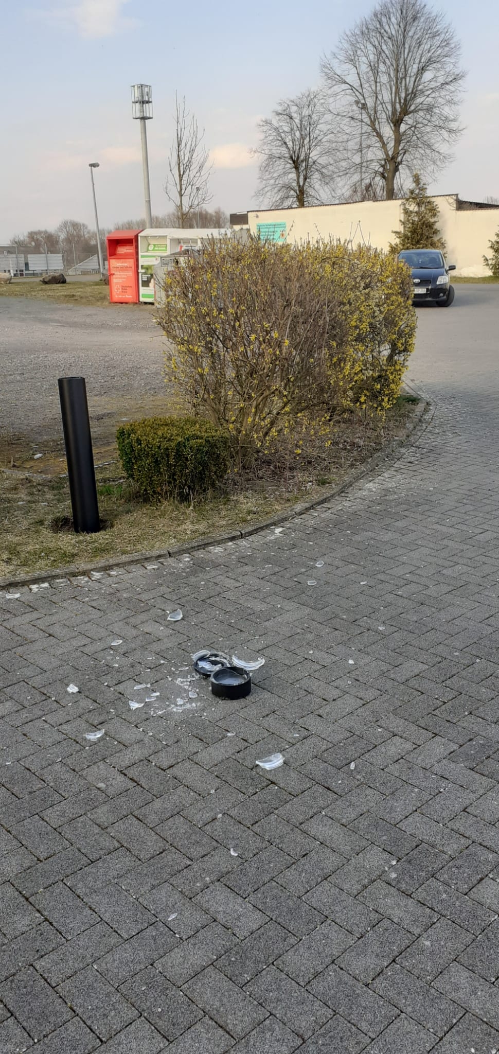 zerstörte Lampe, Glassplitter auf dem Boden am Rand Grasfläche 
