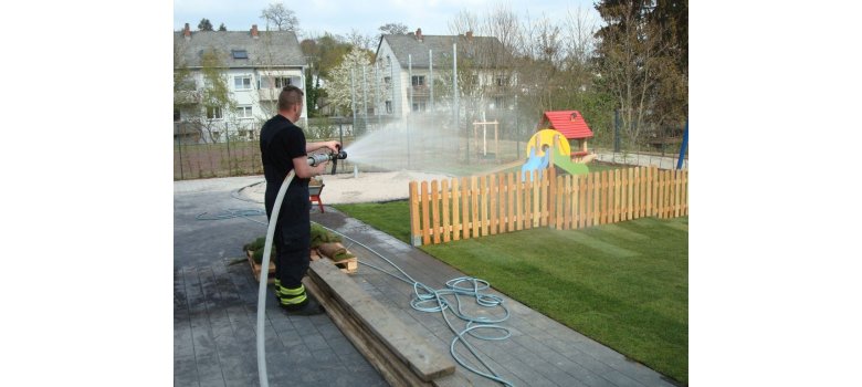 Ein Feuerwehrmann bei der Bewässerung des Rollrasens