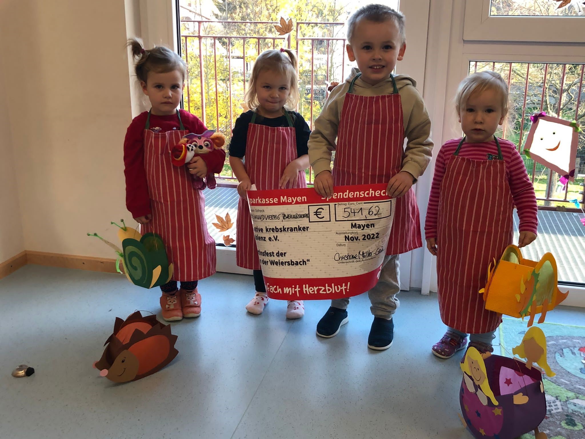 4 Kinder mit einem Scheck in der Hand und gebastelten Laternen 