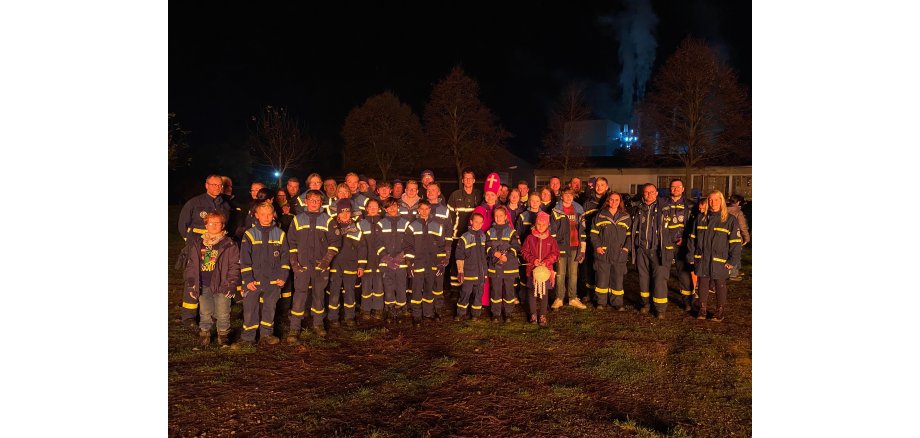 Viele Helfer von Feuerwehr und THW stehen in einem Gruppenbild in der Dunkelheit zusammen - in der Mitte ist St. Martin