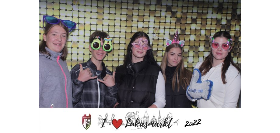 5 Jugendliche mit lustigen Bilden und Kopfschmuck in einer Fotobox