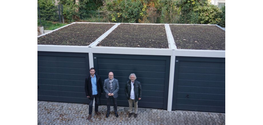 Von links nach rechts: Klimaschutzmanager Helge Lippert, Oberbürgermeister Dirk Meid und Guido Feilzer, Vertriebsleiter Vulkatec GmbH vor den neu begrünten Garagen am Mayener Rathaus.   