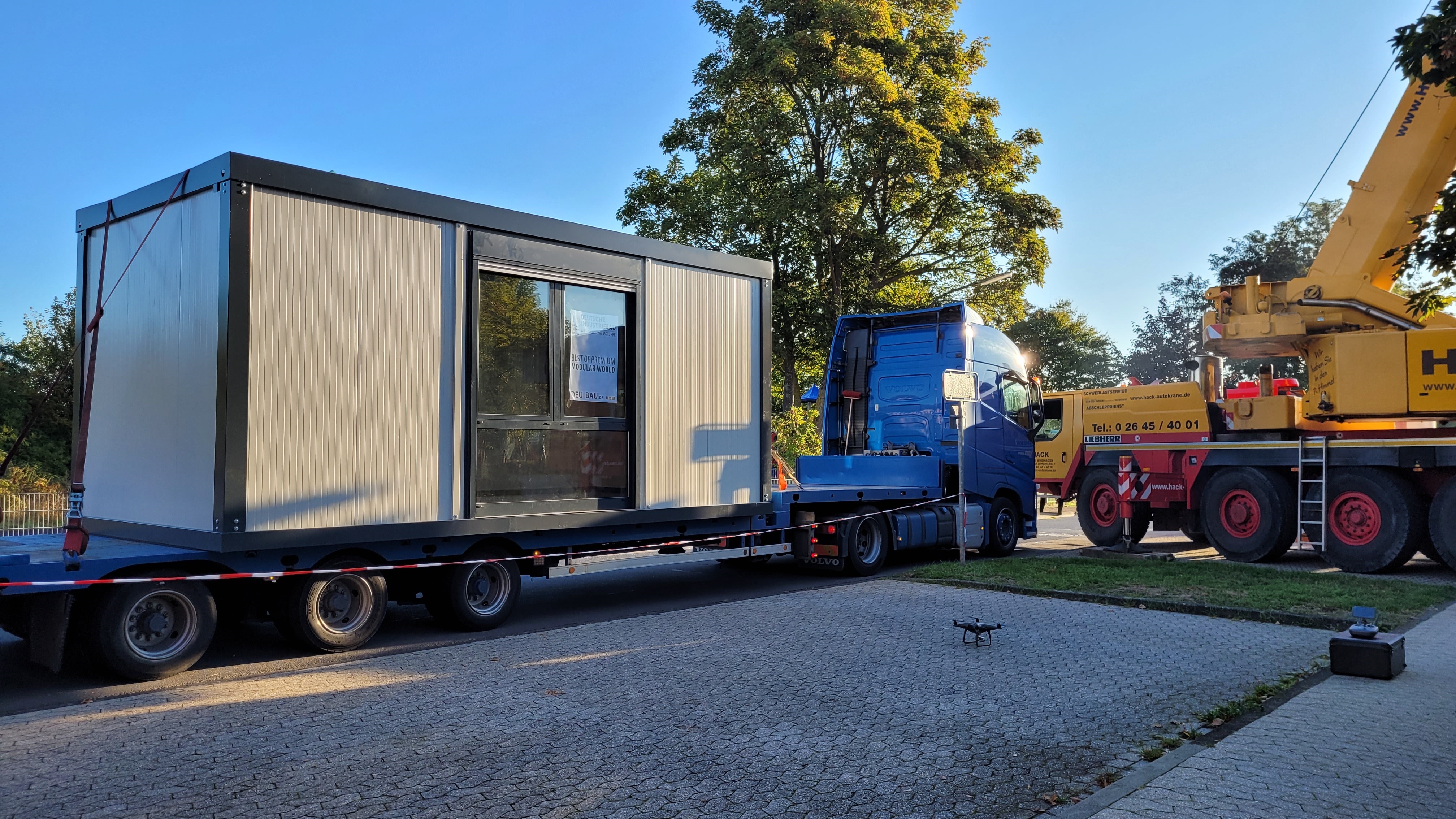 LKW mit einem Container auf der Ladefläche, daneben ein Kran