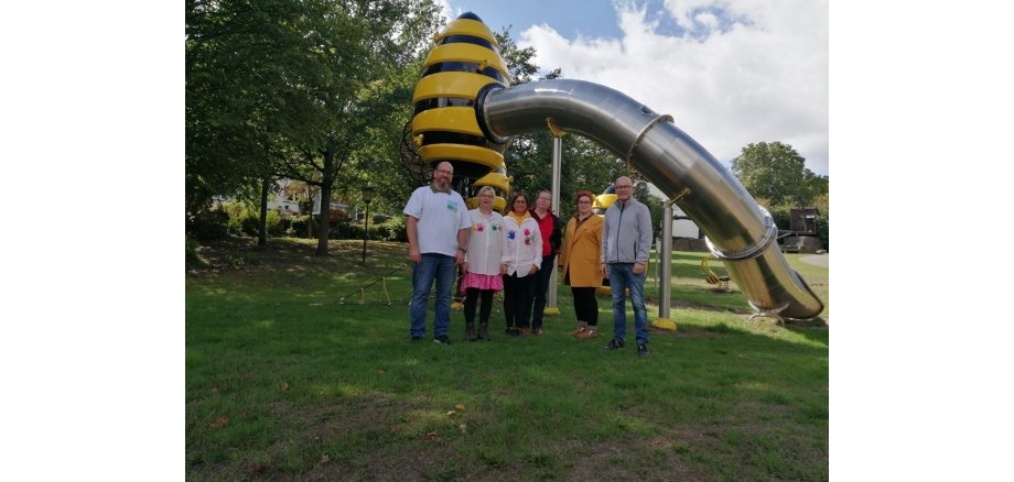 Sechs Personen vor einer Rutsche auf einer Wiese