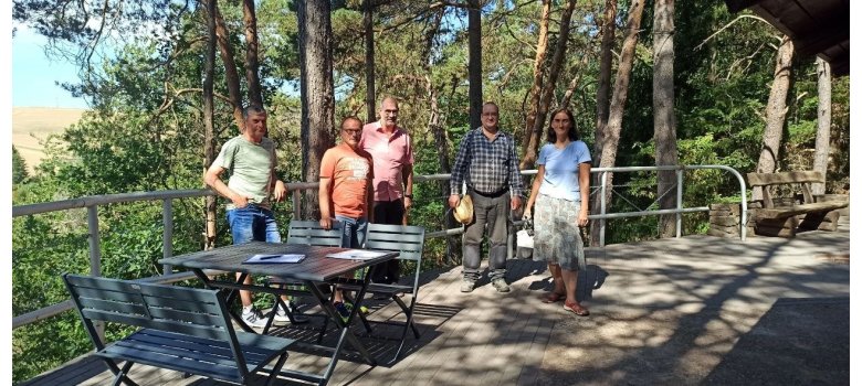 Fünf Personen auf einer Terrasse vor Bäumen