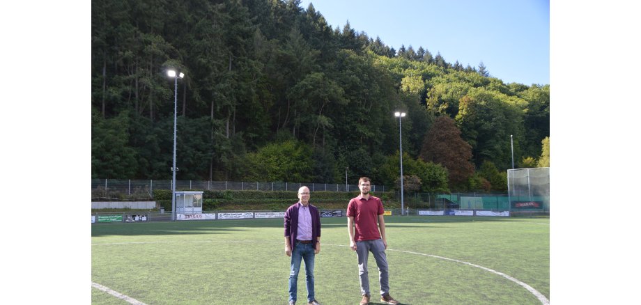 Zwei Personen auf dem Fußballfeld vor den Flutlichtern