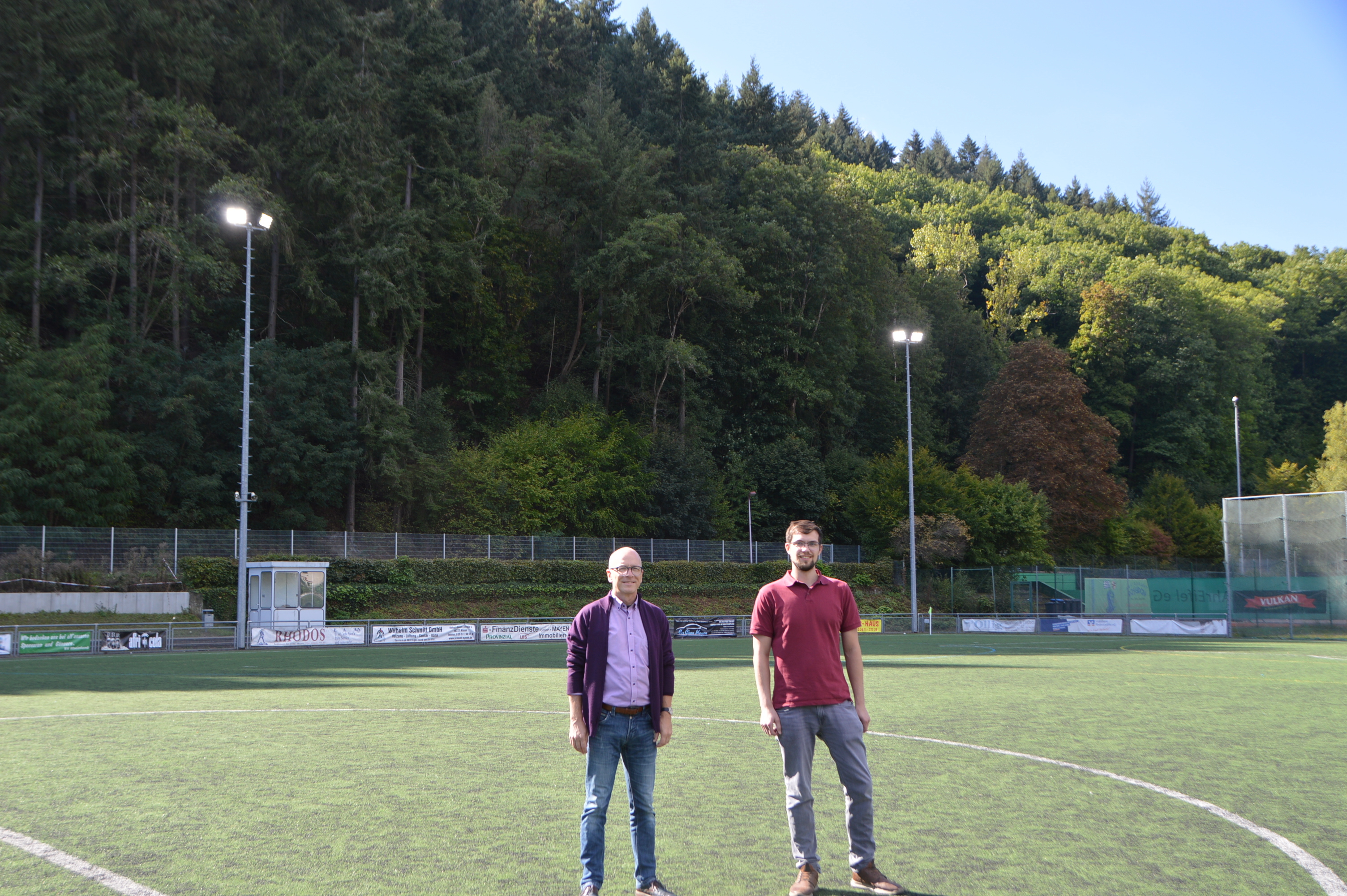 Zwei Personen auf dem Fußballfeld vor den Flutlichtern