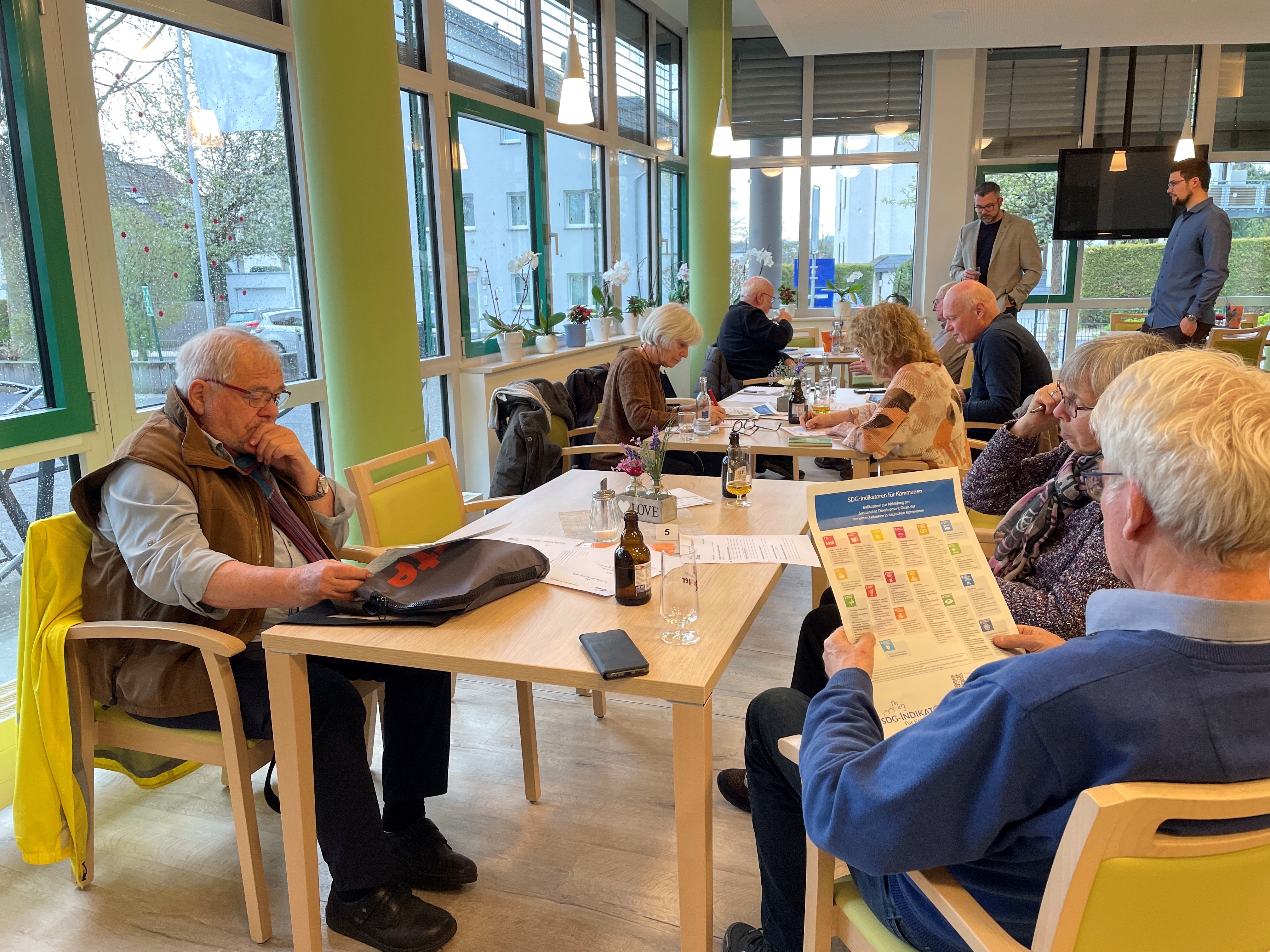 Menschen sitzen zusammen am Tischen und tauschen sich aus