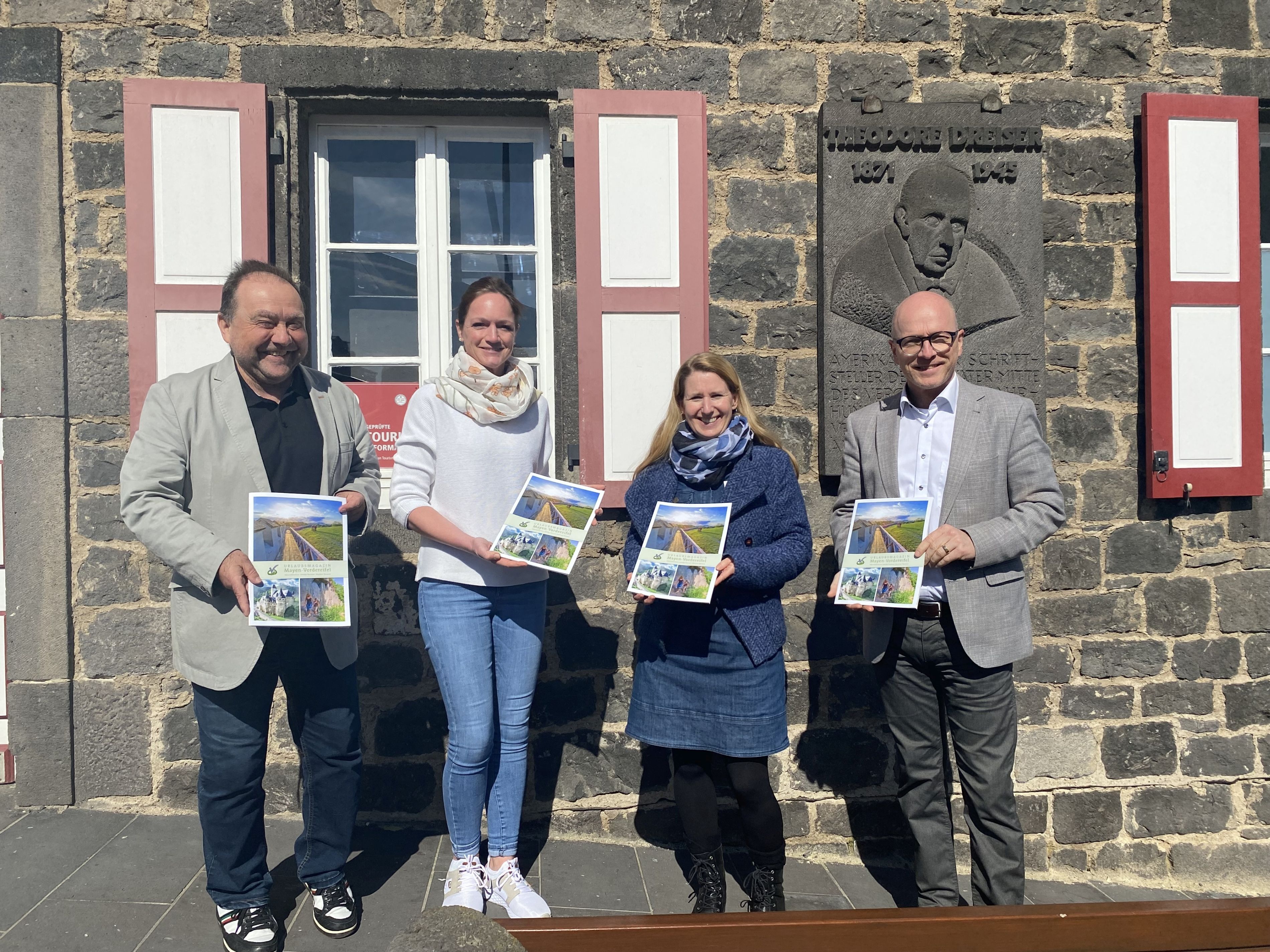 Vier Personen stehen vor der Tourist-Info und präsentieren das neue Urlaubsmagazin