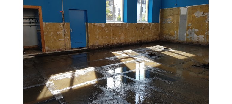 Sporthalle nach der Flutkatastrophe Boden und Wände der Sporthalle nach einer Flut - auf dem Boden überall Wasser
