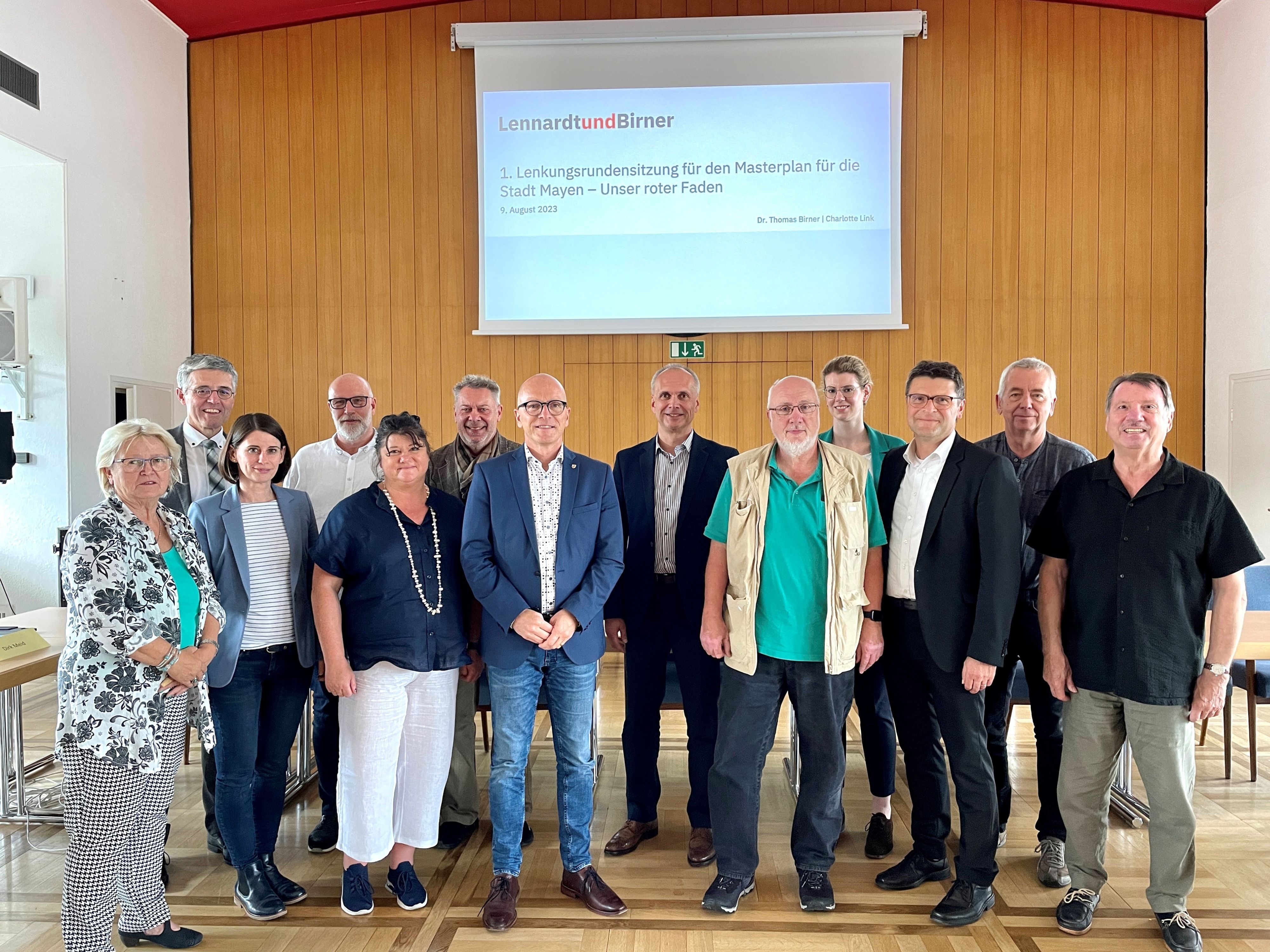 Eine Gruppe steht im Sitzungssaal zur Lenkungsrunde versammelt