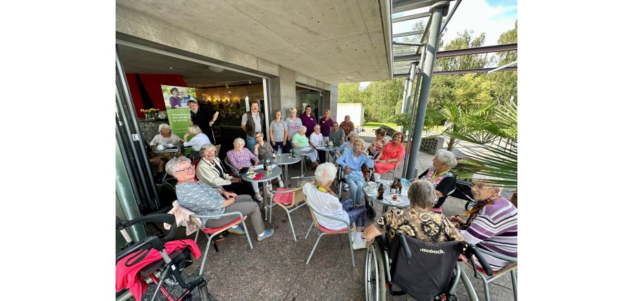 Viele Menschen sitzen bei Kaffee und Kuchen zusammen und tauschen sich aus