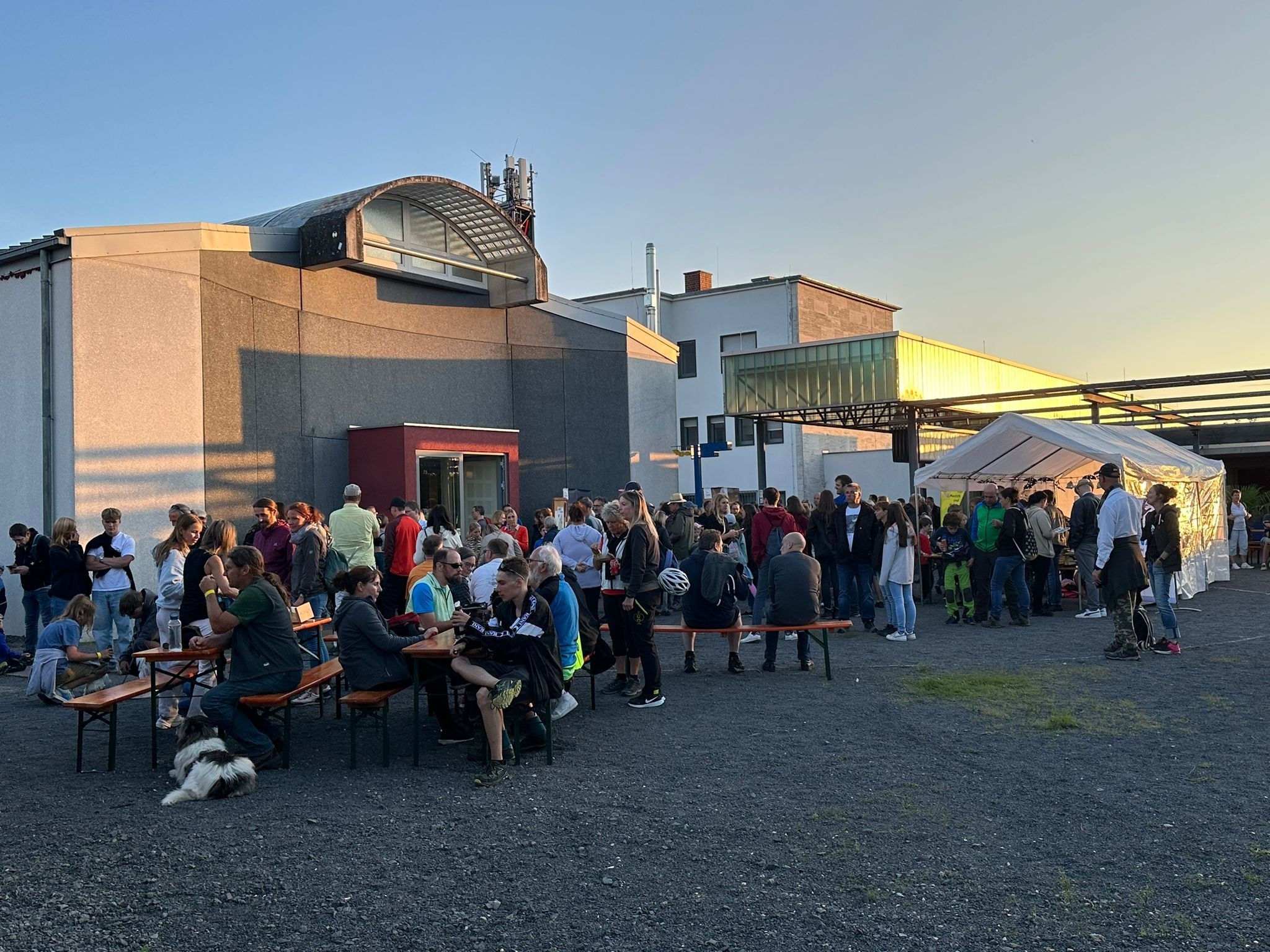 Viele Menschen stehen in Gruppen zusammen - die Sonne geht unter 