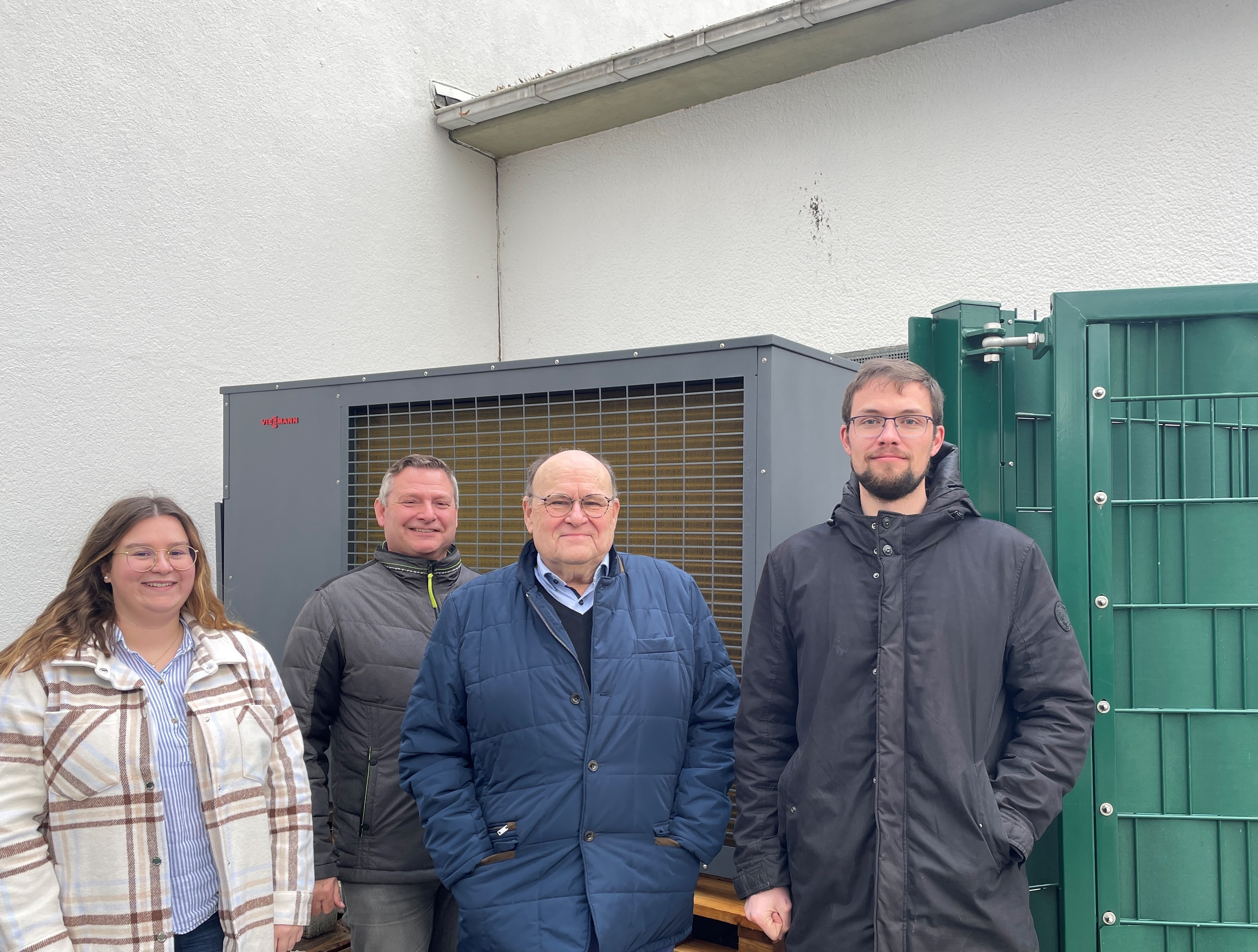 4 Personen stehen vor einer Wärmepumpe