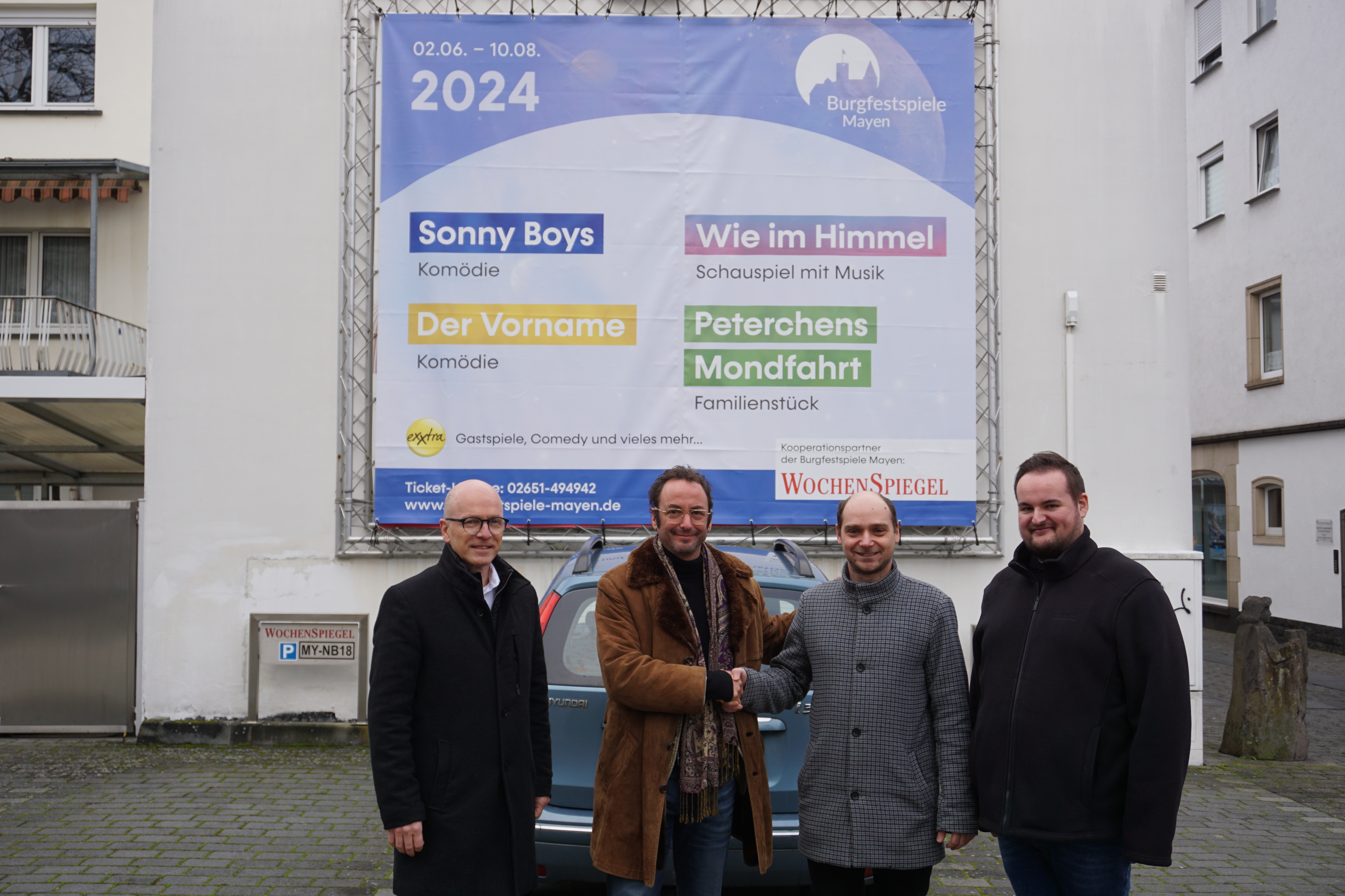 Vier Personen stehen vor dem Werbebanner am Wochenspiegel