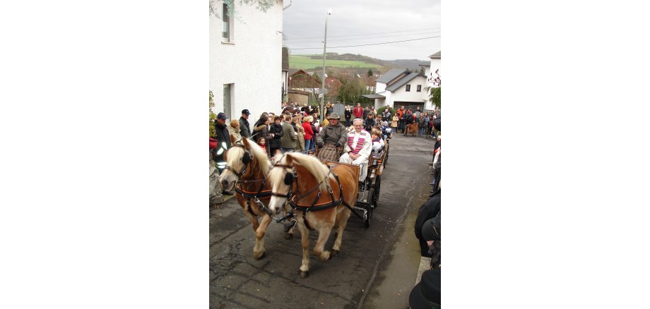 Der Silvesterritt gilt als langjährige Tradition und zieht viele Besucher an Eine Pferdekutsche mit Personen fährt durch die Hausener Straßen