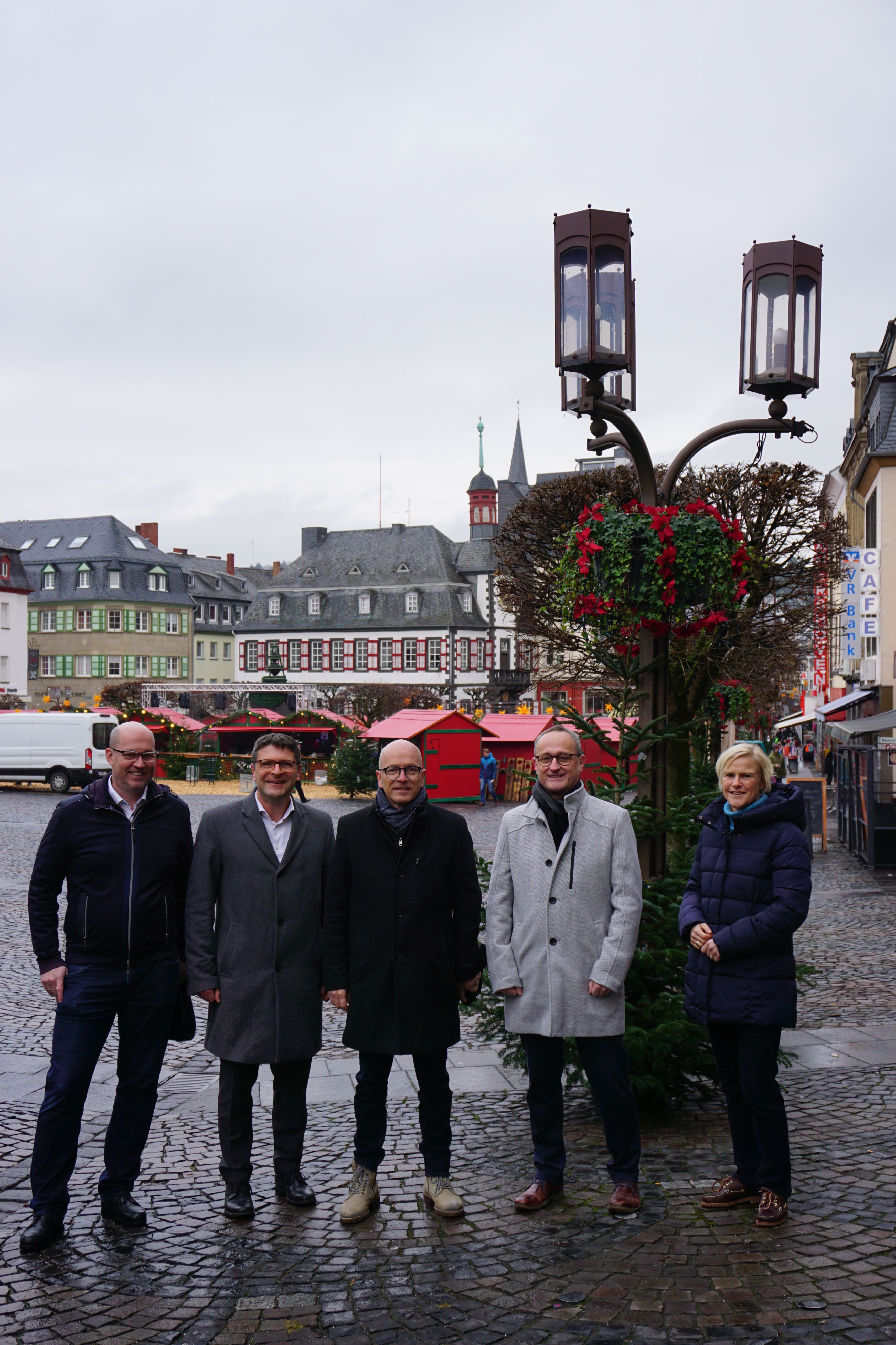 Fünf Personen in der Innenstadt vor den Blumenampeln