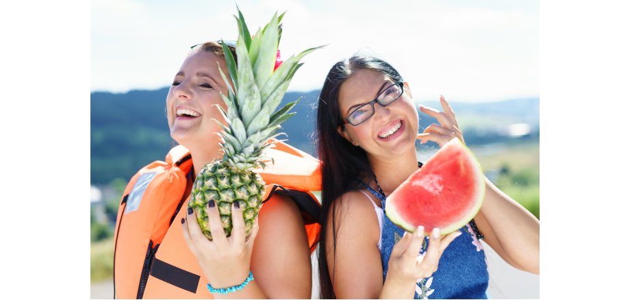 2 Frauen mit einer Ananas und einer Melone in der Hand