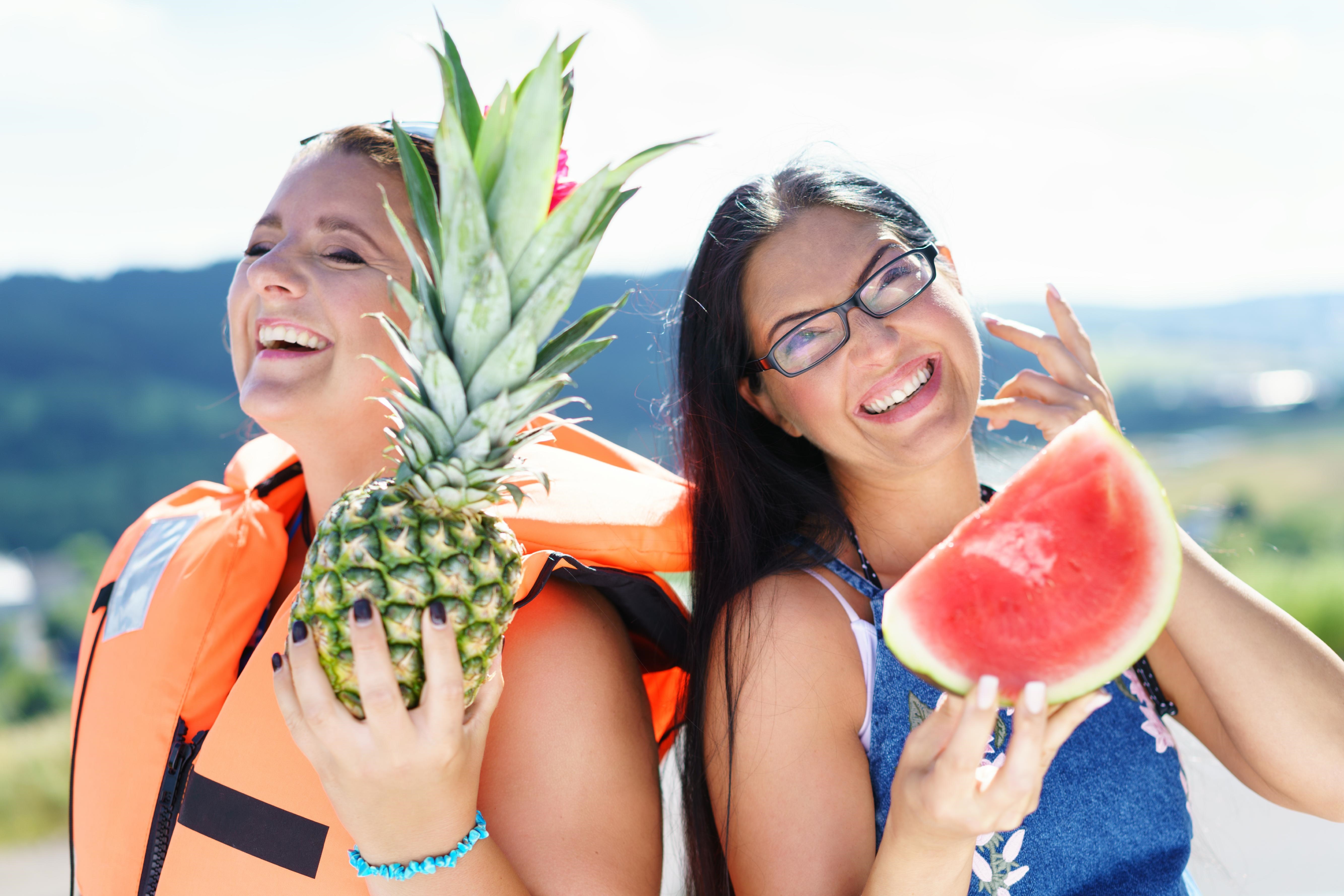 2 Frauen mit einer Ananas und einer Melone in der Hand