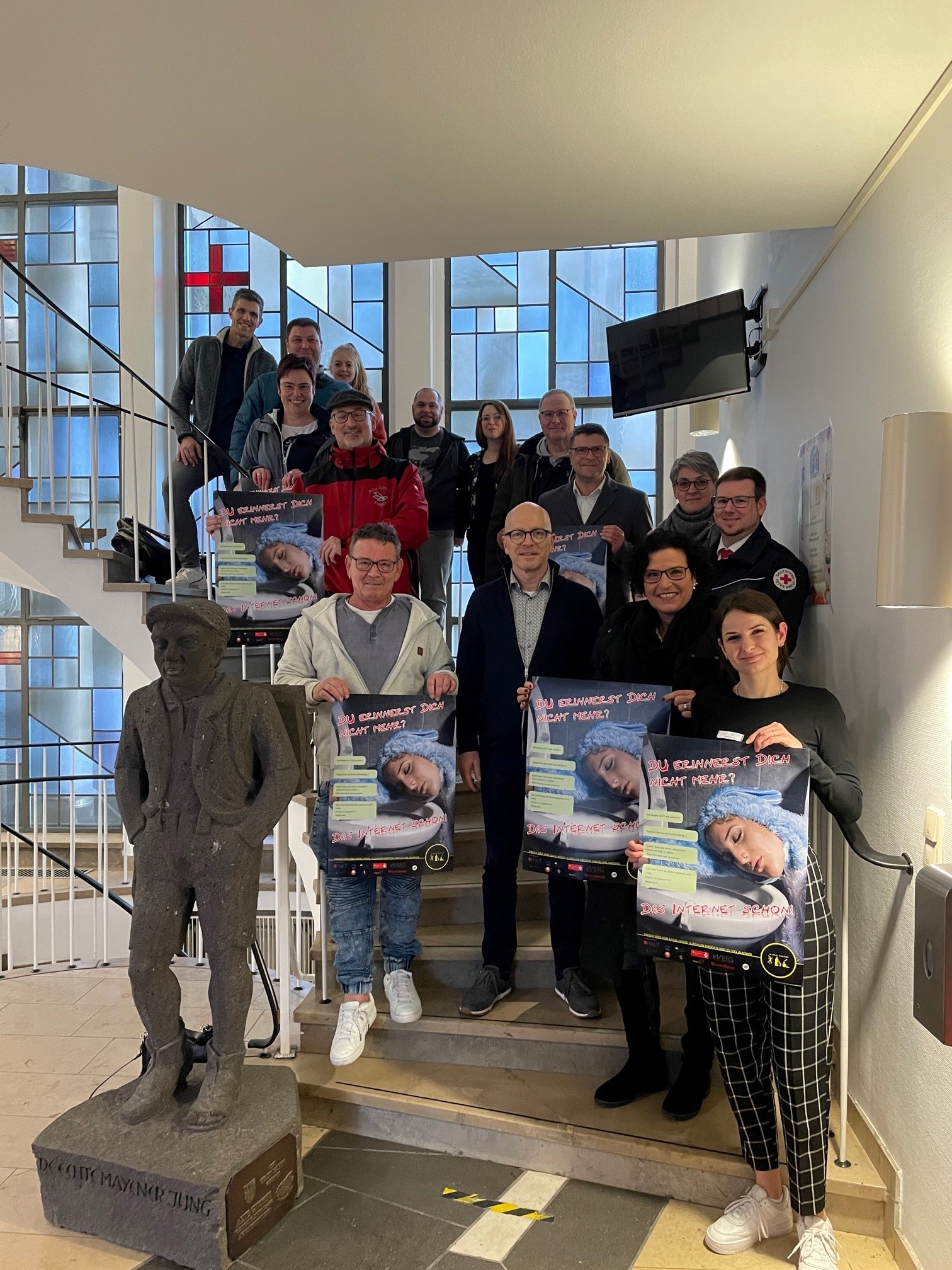 Verschiedene Personen stehen mit Plakaten in den Händen auf einer Treppe