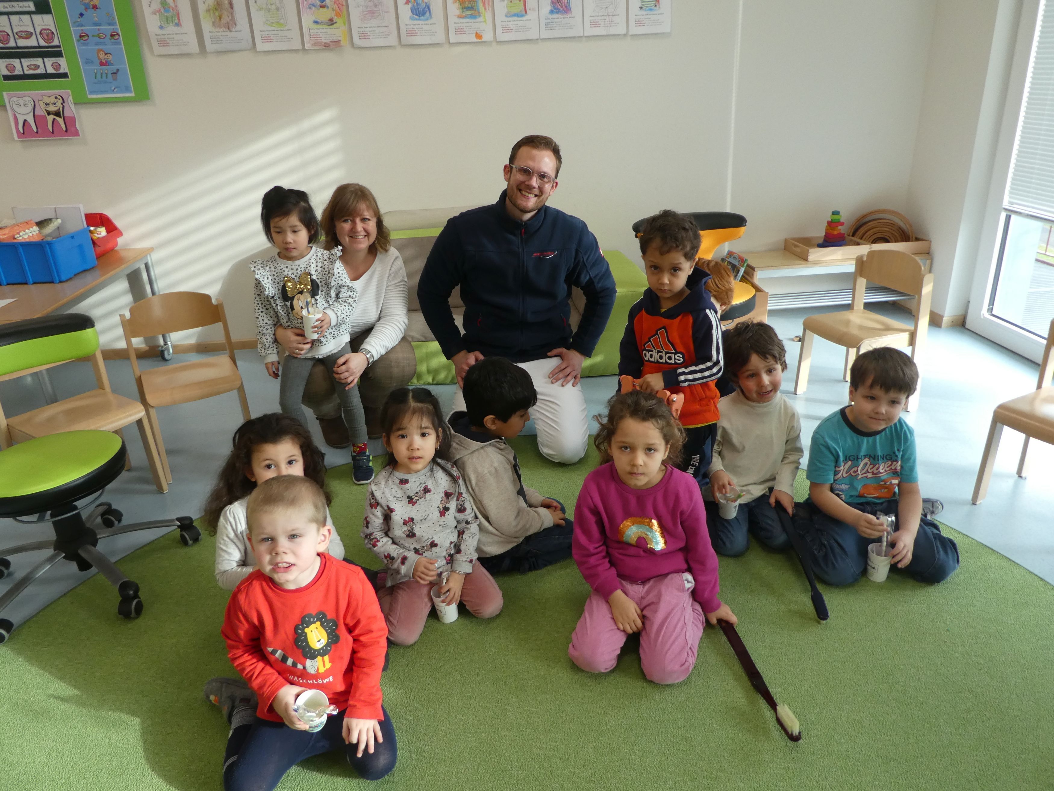 2 Erwachsene mit Kindern kniende auf einem Teppich