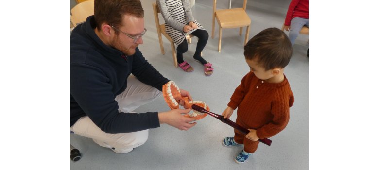Zahnarzt Dr. Apeldorn klärt die Kinder der KiTa „In der Weiersbach“ über Zahnhygiene auf. Mann erklärt einem Kind alles rund um das menschliche Gebiss