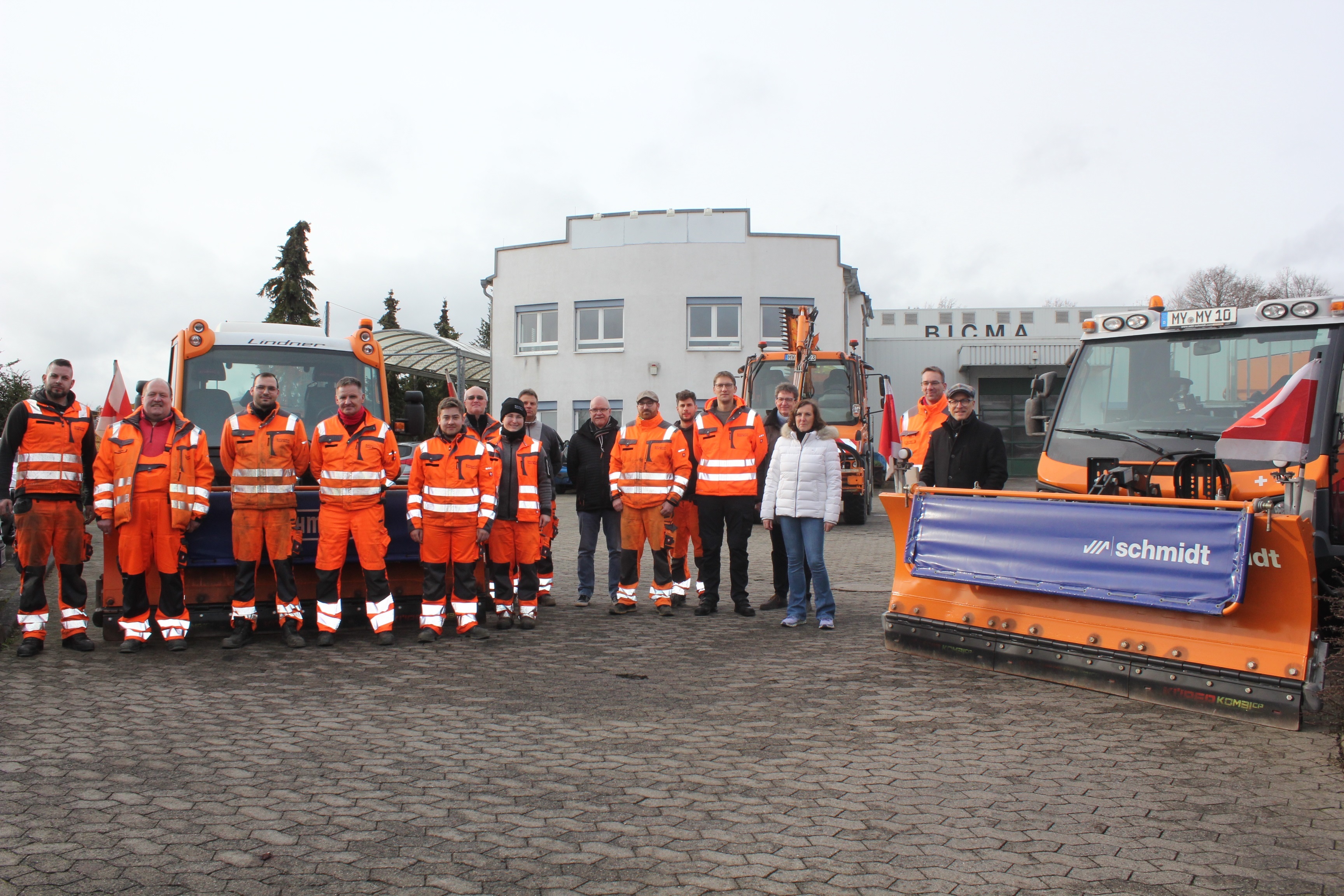 Zahlreiche Personen stehen vor Fahrzeugen des Betriebshofes - viele sind in Organge gekleidet