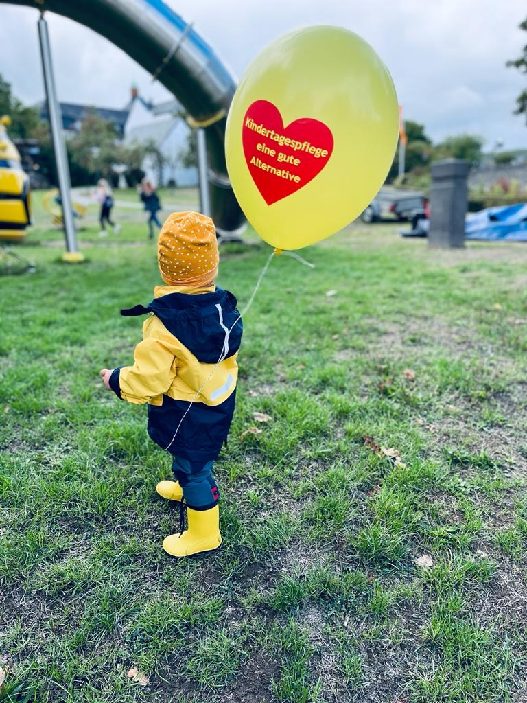 Kleines Kind mit einem Luftballon mit den Worten "Kindertagespflege eine gute Alternative"