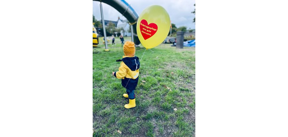 Kleines Kind mit einem Luftballon mit den Worten "Kindertagespflege eine gute Alternative"
