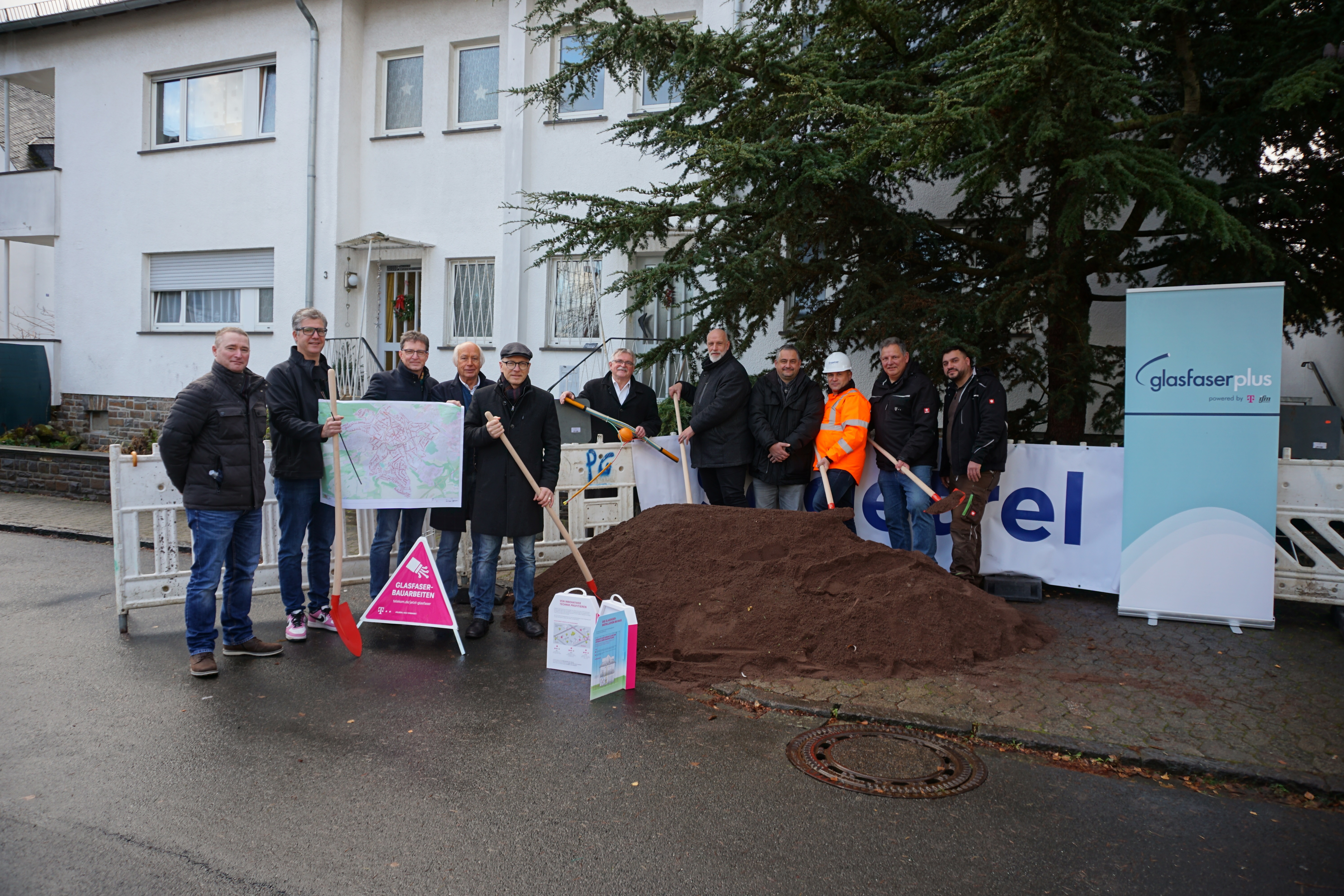 11 Personen mit Schaufeln in der Hand an einer Baustelle