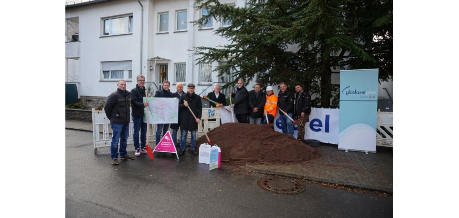 11 Personen mit Schaufeln in der Hand an einer Baustelle