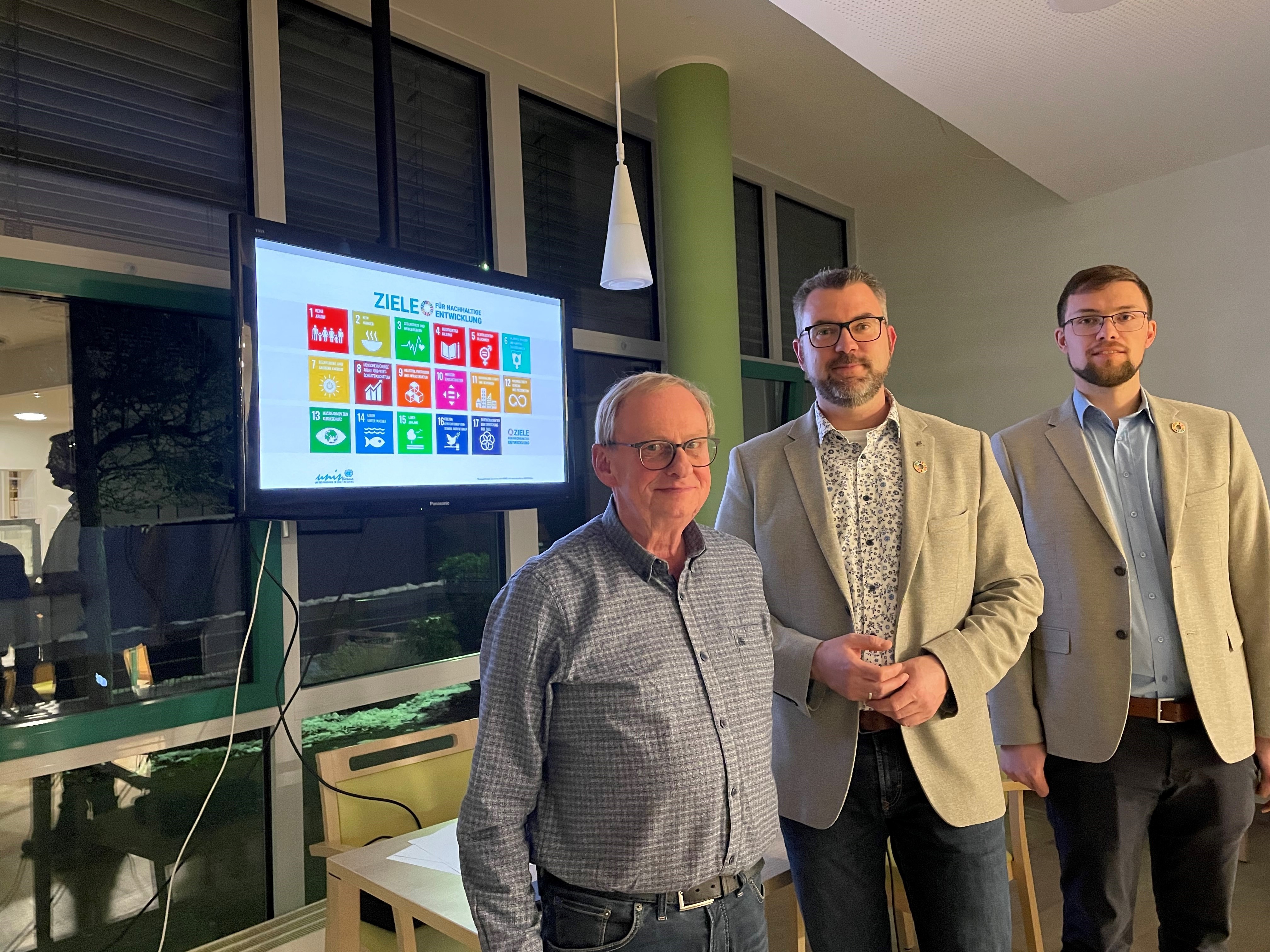 Drei Männer stehen vor einem Fernseher 