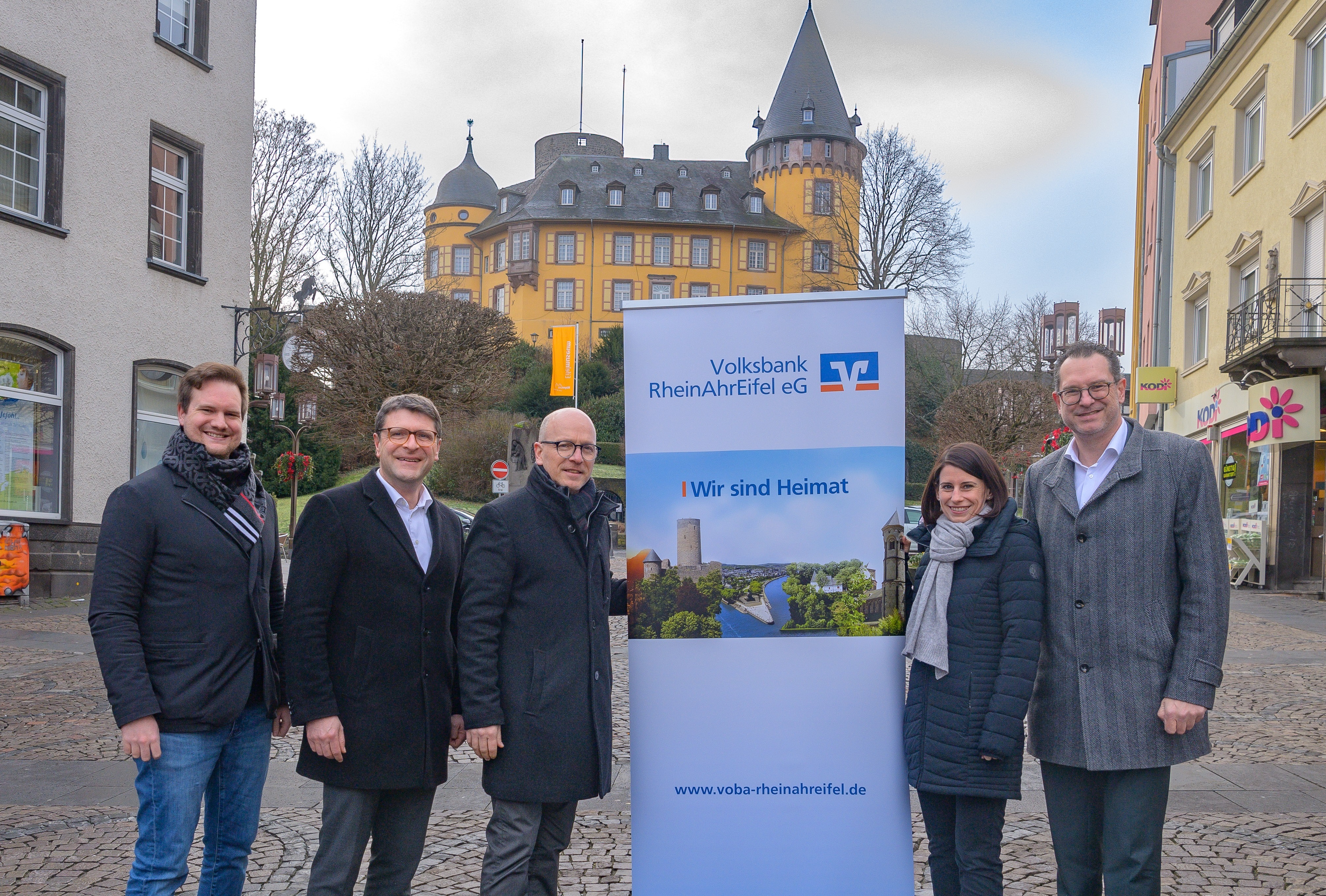 5 Personen stehen neben einem Aufstellbanner vor der Genovevaburg