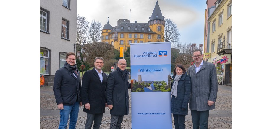 5 Personen stehen neben einem Aufstellbanner vor der Genovevaburg