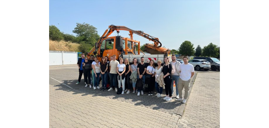 Eine Gruppe von Personen steht vor einem Arbeitsfahrzeug des Betriebshofes für ein Bild zusammen