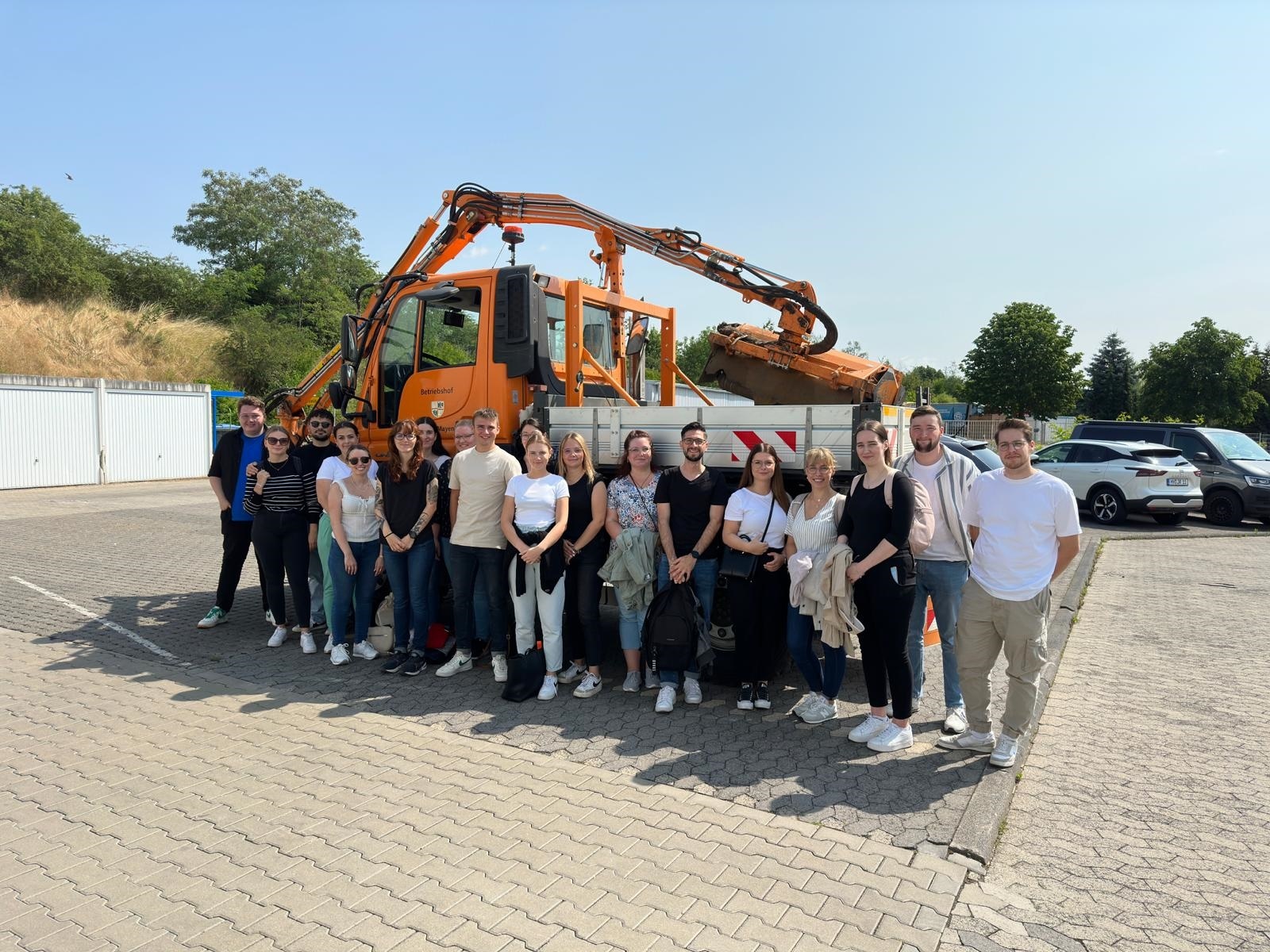 Eine Gruppe von Personen steht vor einem Arbeitsfahrzeug des Betriebshofes für ein Bild zusammen
