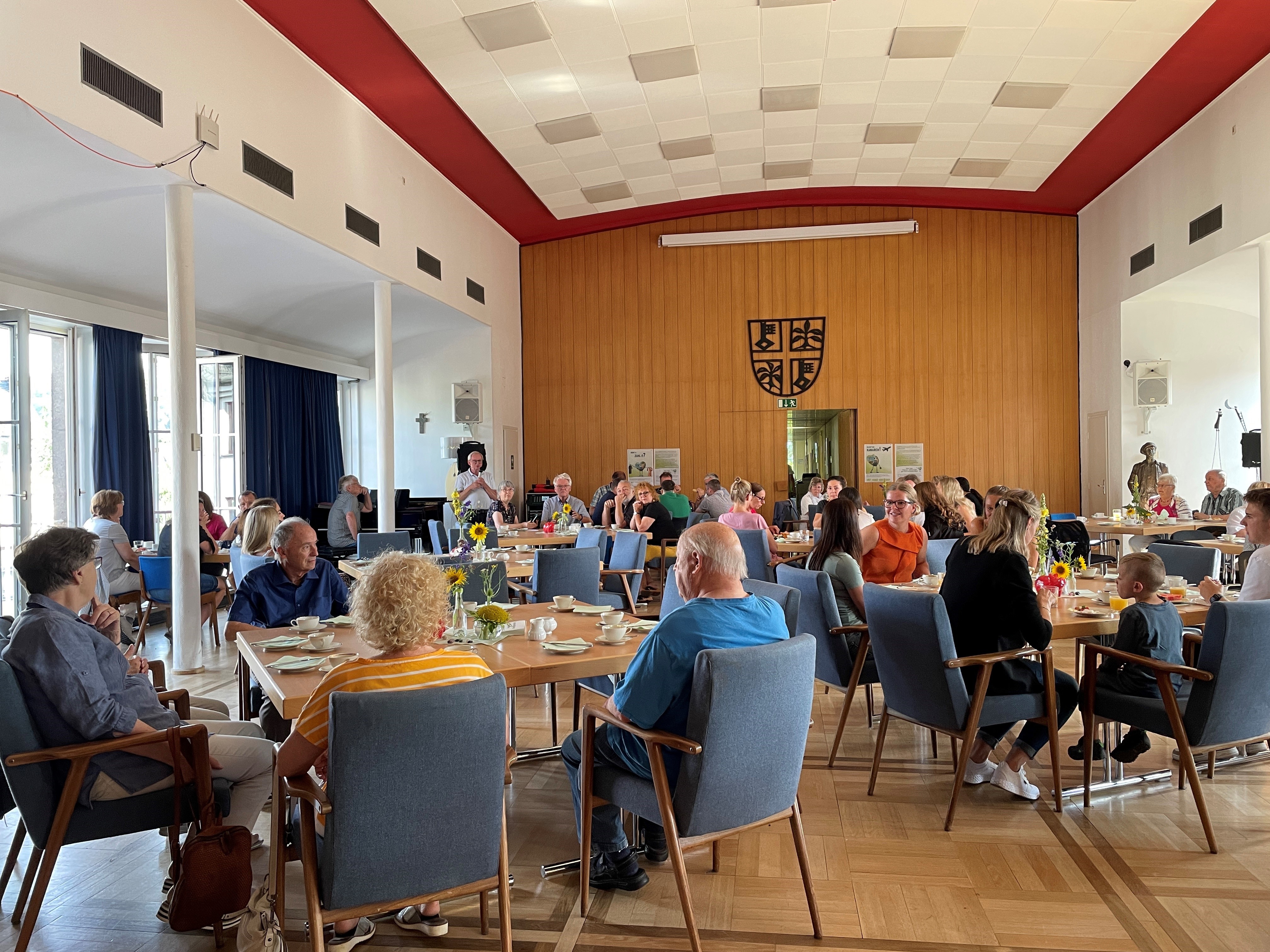 Viele Gäste beim diesjährigen Fairen Frühstück freuen sich über faire und regionale Produkte Sitzungssaal mit Stühlen und gedeckten Tischen und voller Leute