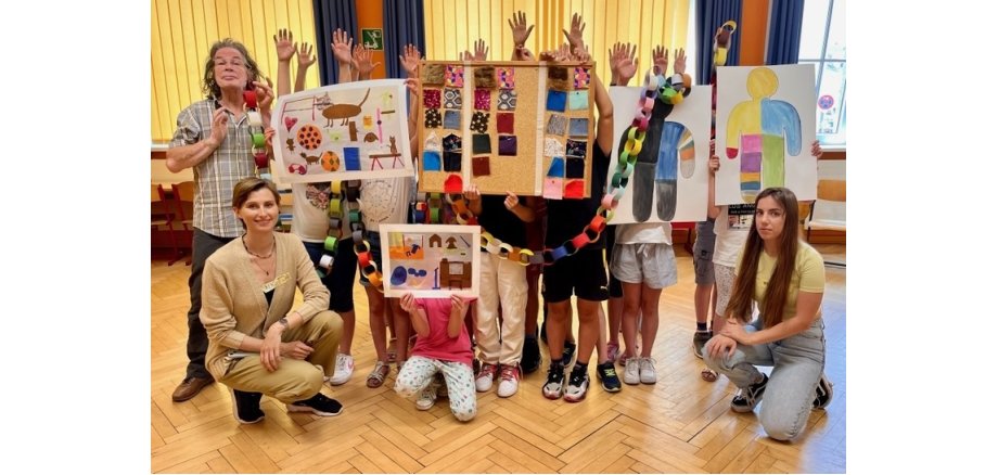 3 Erwachsene und Kinder stehen in einer Gruppe zusammen - die Kinder sind alle durch Plakate verdeckt