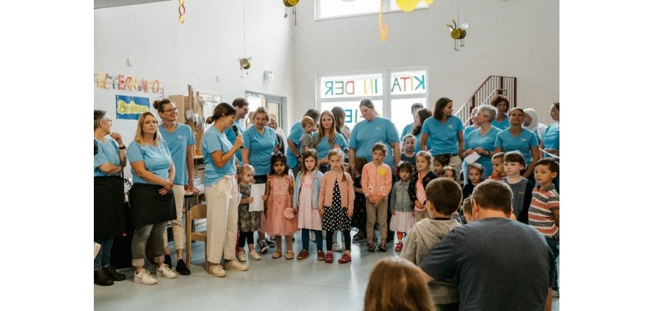 Erzieher*innen und Kinder stehen zu einem Gruppenfoto zusammen