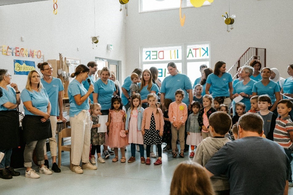 Erzieher*innen und Kinder stehen zu einem Gruppenfoto zusammen