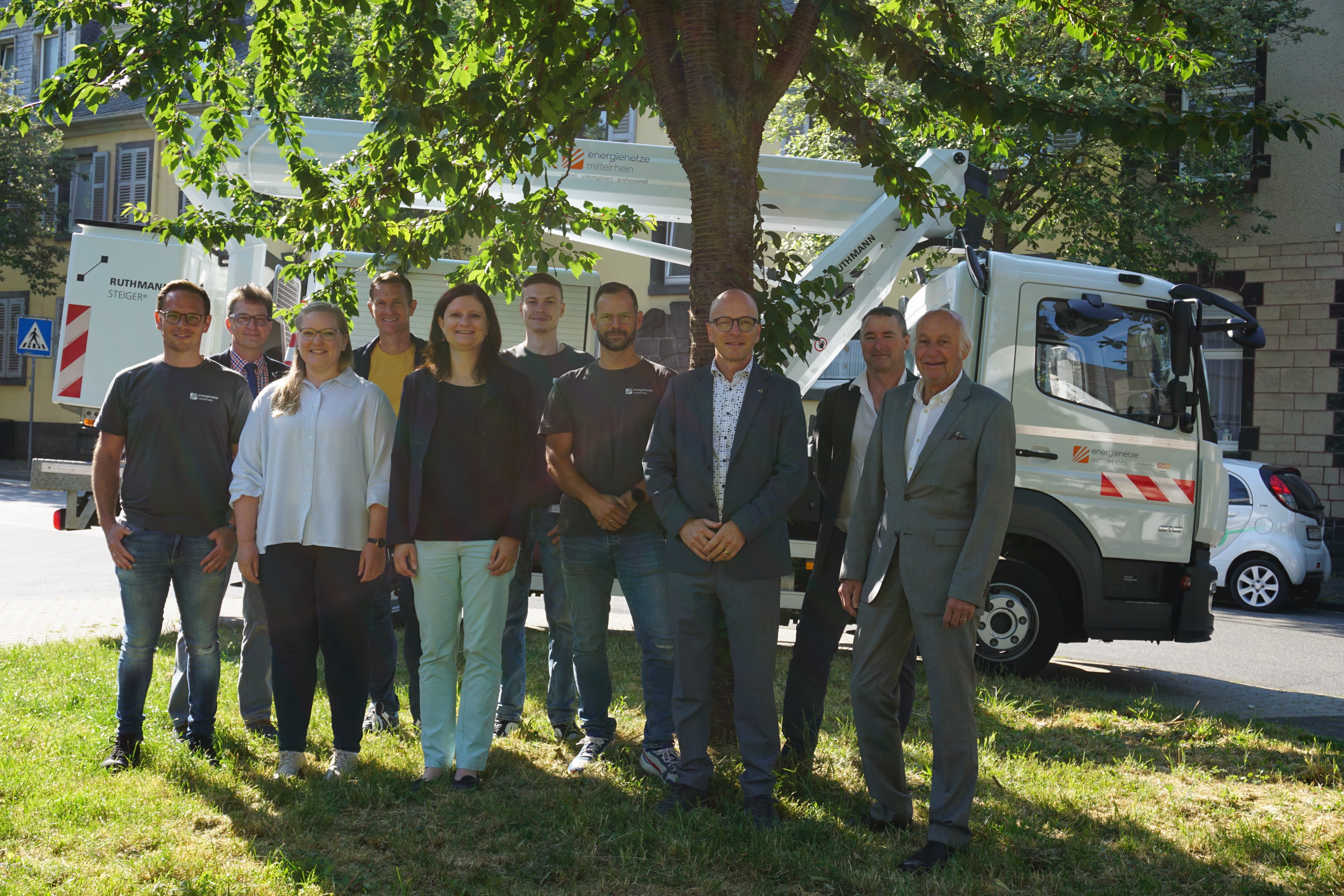 Gruppe von Personen steht unter einem Baum für ein Bild zusammen