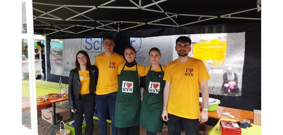 5 Personen stehe unter einem Pavillon - alle haben gelbe T-Shirts an