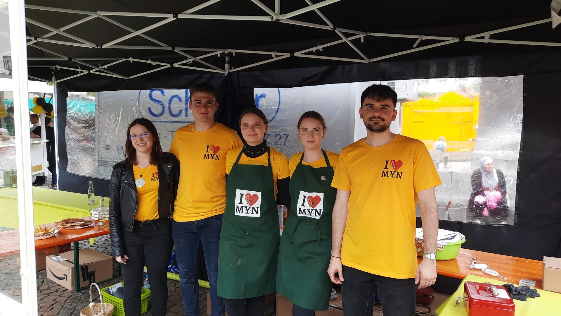 5 Personen stehe unter einem Pavillon - alle haben gelbe T-Shirts an