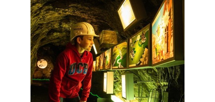 Junge mit Helm schaut sich in einem unterirdischen Tunnel etwas an